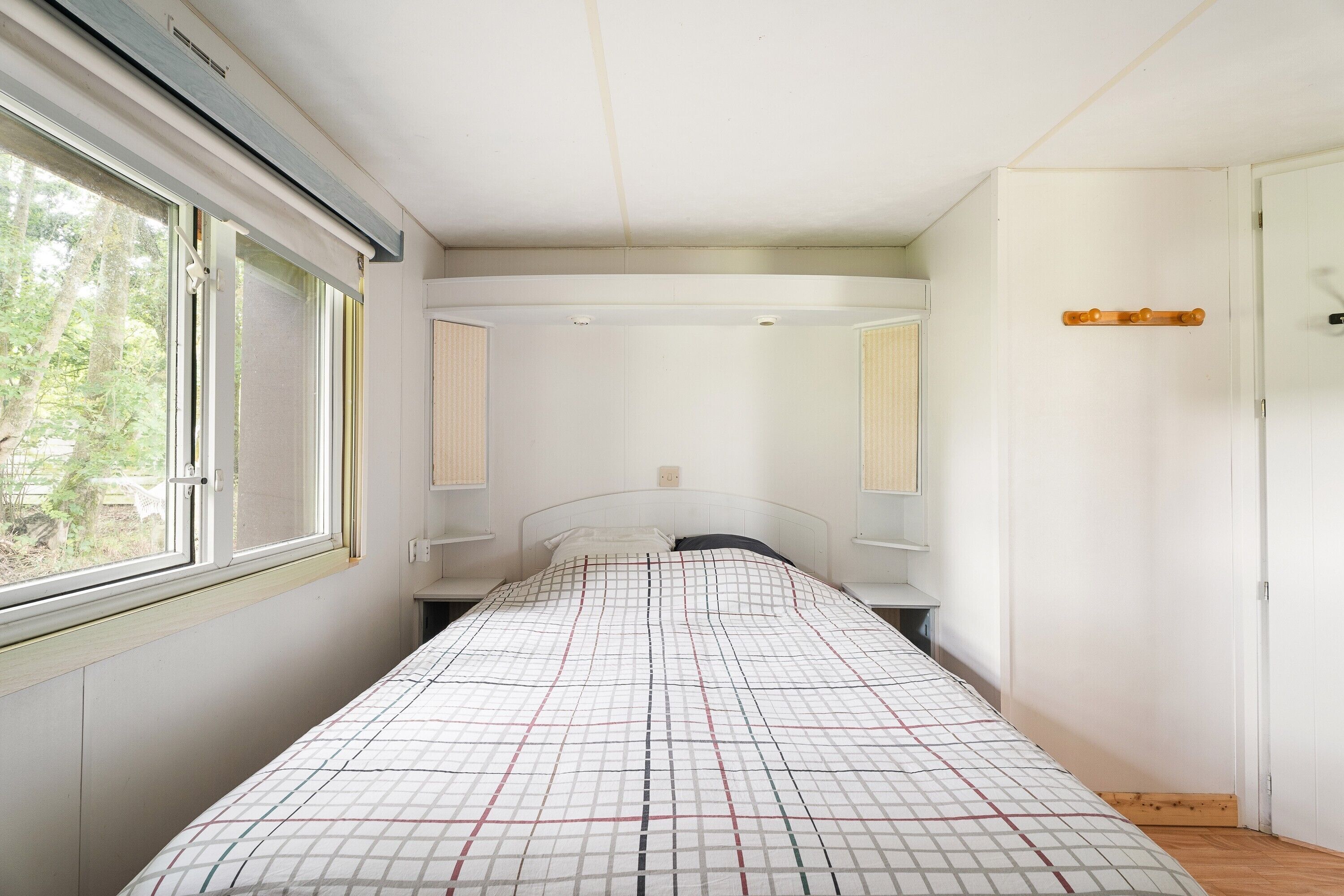 Une chambre à coucher avec un lit, une fenêtre, une porte et un interrupteur sur le mur.