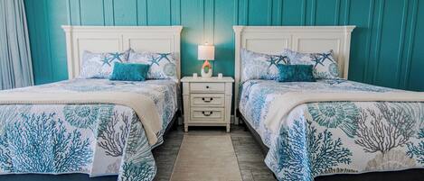 A room with two beds, a nightstand, and a lamp.