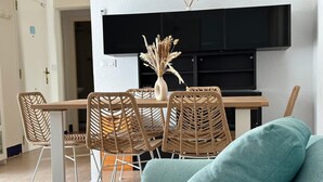 Ett modernt vardagsrum med en matplats, en soffa och en platt-TV som är monterad på väggen.