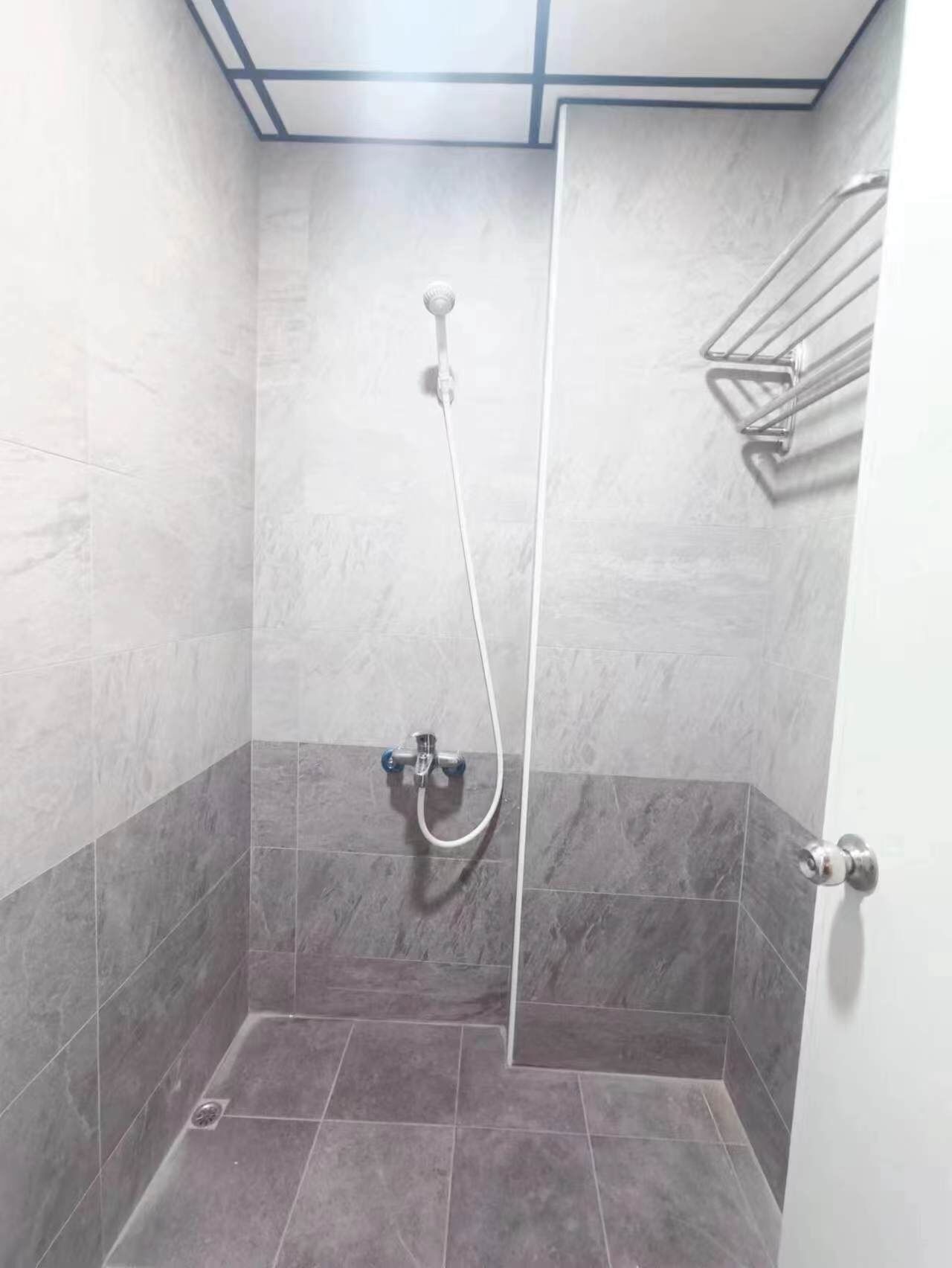 Un pequeño baño con azulejos, una ducha y un grifo.