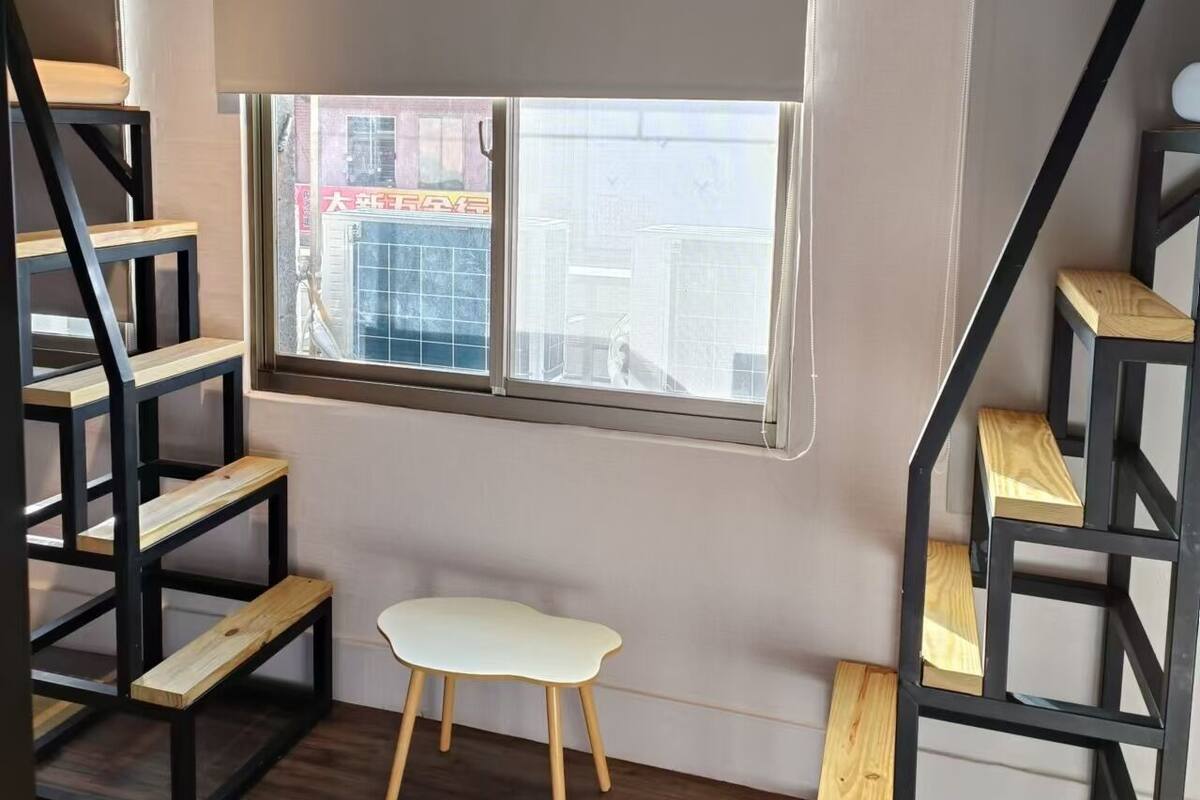 Ein Zimmer mit Holzboden, einem weißen Stuhl und schwarzen Holzstufen.