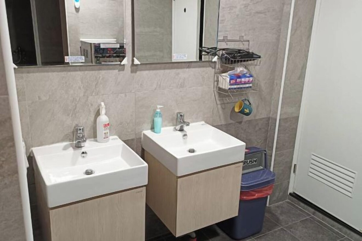 A bathroom with two sinks, a mirror, and a trash bin.