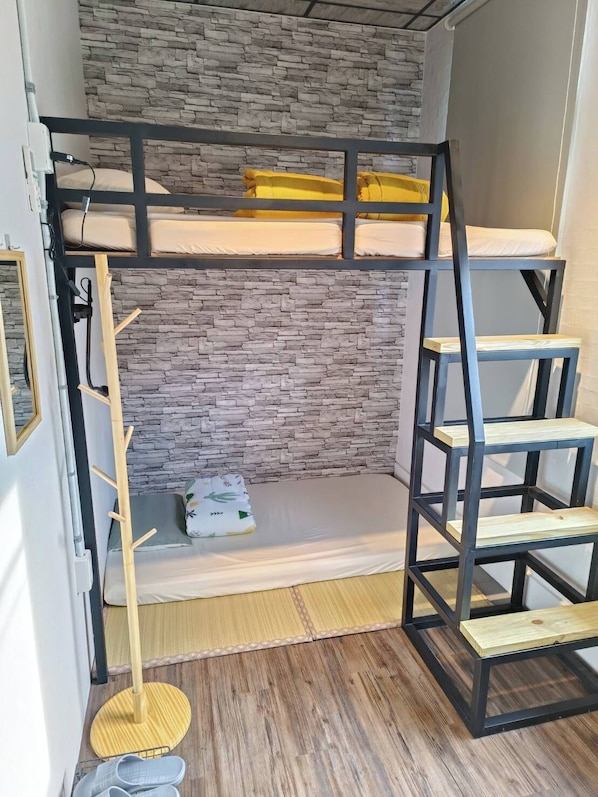 A bunk bed with a stone wall backdrop, a wooden ladder, and a small shelf. - North Coast Hostel (New Taipei City)
