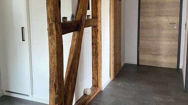 Una habitación con estructura de madera, una puerta blanca y una puerta de madera con manija.