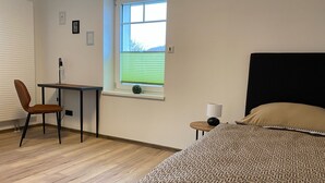 Un dormitorio con cama, escritorio, silla y ventana con persianas.