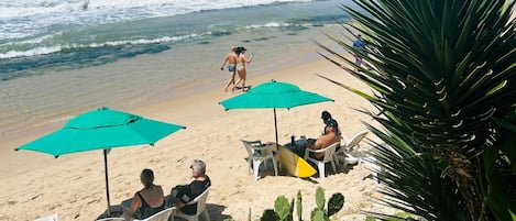 En la playa, arena blanca, sillas reclinables de playa, sombrillas