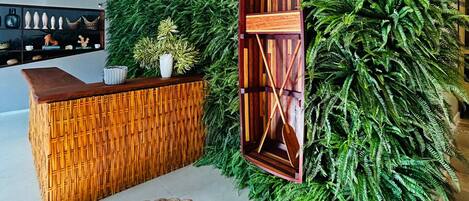 A reception area with a wooden reception desk, a large green wall, and hanging pendant lights.