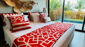 Un dormitorio moderno con una cama grande, un adorno en la pared y vistas a una piscina y palmeras.