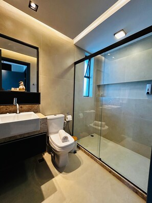 Ein modernes Badezimmer mit einer gläsernen Duschkabine, einem Waschbecken und einer Toilette.