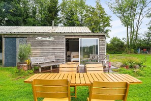 Una baita in legno con un cartello che riporta 'LA GRANGE TOURS', un patio con mobili in legno e una zona giardino.