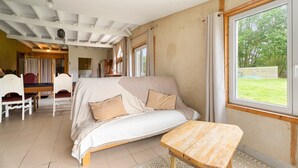 A room with a bed, a wooden table, and a view of the outdoors. - Holiday Home 'Gîte Pour 4 Avec Sauna' with Shared Garden (Broons)