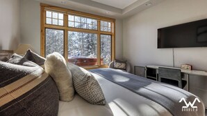 Ein Schlafzimmer mit großem Fenster, einem Bett, einem Schreibtisch und einem Fernseher.