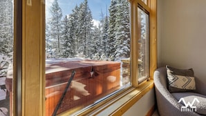 Ein Zimmer mit einem großen Fenster mit Blick auf eine verschneite Landschaft und Bäume.