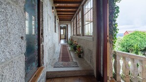 A corridor with stone walls, wooden beams, and a view of greenery outside. - Country House 'Casa Rural Magina' with Mountain View, Private Terrace and Wi-Fi (Fornelos de Montes)