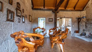 A rustic interior with stone walls, wooden beams, and a dining area with carved wooden chairs. - Country House 'Casa Rural Magina' with Mountain View, Private Terrace and Wi-Fi (Fornelos de Montes)