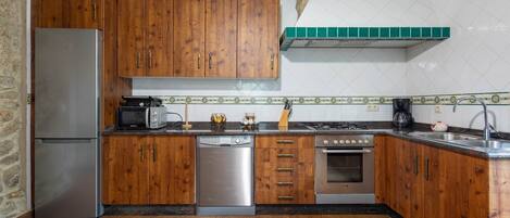 Una cucina con mobili in legno, un frigorifero in acciaio inossidabile, una lavastoviglie, un piano cottura e un lavello.