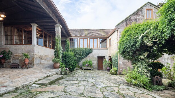 A stone courtyard with a wooden pergola, stone steps, and potted plants. - Country House 'Casa Rural Magina' with Mountain View, Private Terrace and Wi-Fi (Fornelos de Montes)