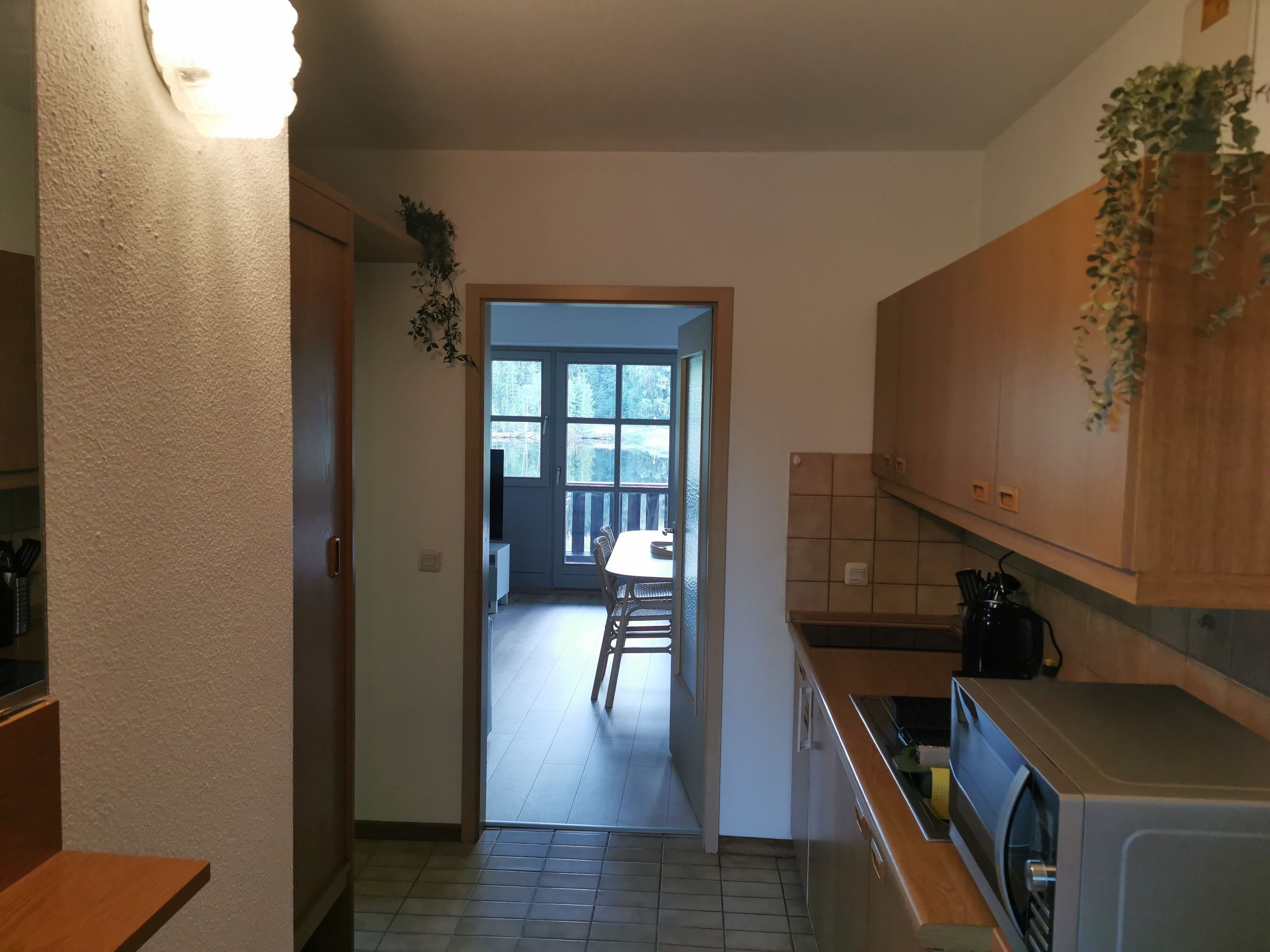 Eine kompakte Küche mit Waschmaschine, Holzschränken und Blick auf einen Balkon.