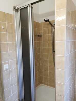 A shower with a handheld showerhead, a shower curtain, and tiled walls. - Appartement am See (Haidmühle)