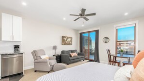 A modern hotel room with a bed, a sofa, a dining table, and a kitchen area. - Modern studio with huge balcony overlooking main street in Grand Lake (Grand Lake)