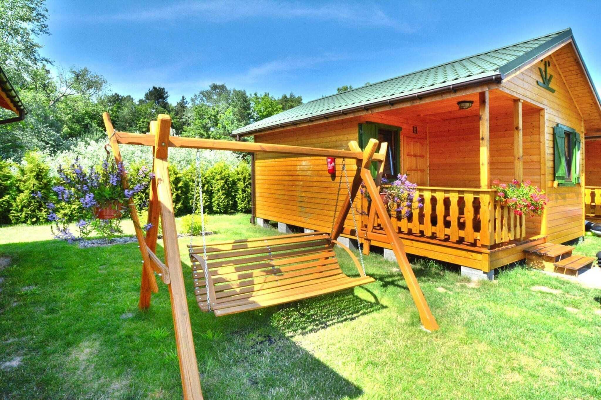 A wooden cabin with a porch, surrounded by a garden with purple flowers.