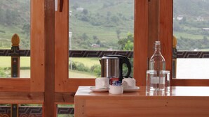 A wooden table with a coffee maker, two cups, and two glasses.
