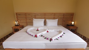 A neatly made bed with white linens and a heart-shaped decoration on the bedspread.