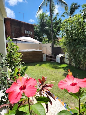 Quintal residencial com piscina, varanda coberta e escada para o segundo andar.