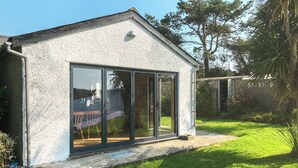A small, single-story building with a white exterior and large sliding glass doors. - 4 bedroom accommodation in Tudweiliog (Tudweiliog)