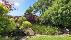 A garden with a variety of plants, a small stream, and a white bird. - 4 bedroom accommodation in Tudweiliog (Tudweiliog)