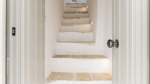 A staircase with stone steps and white walls, leading to a higher floor.