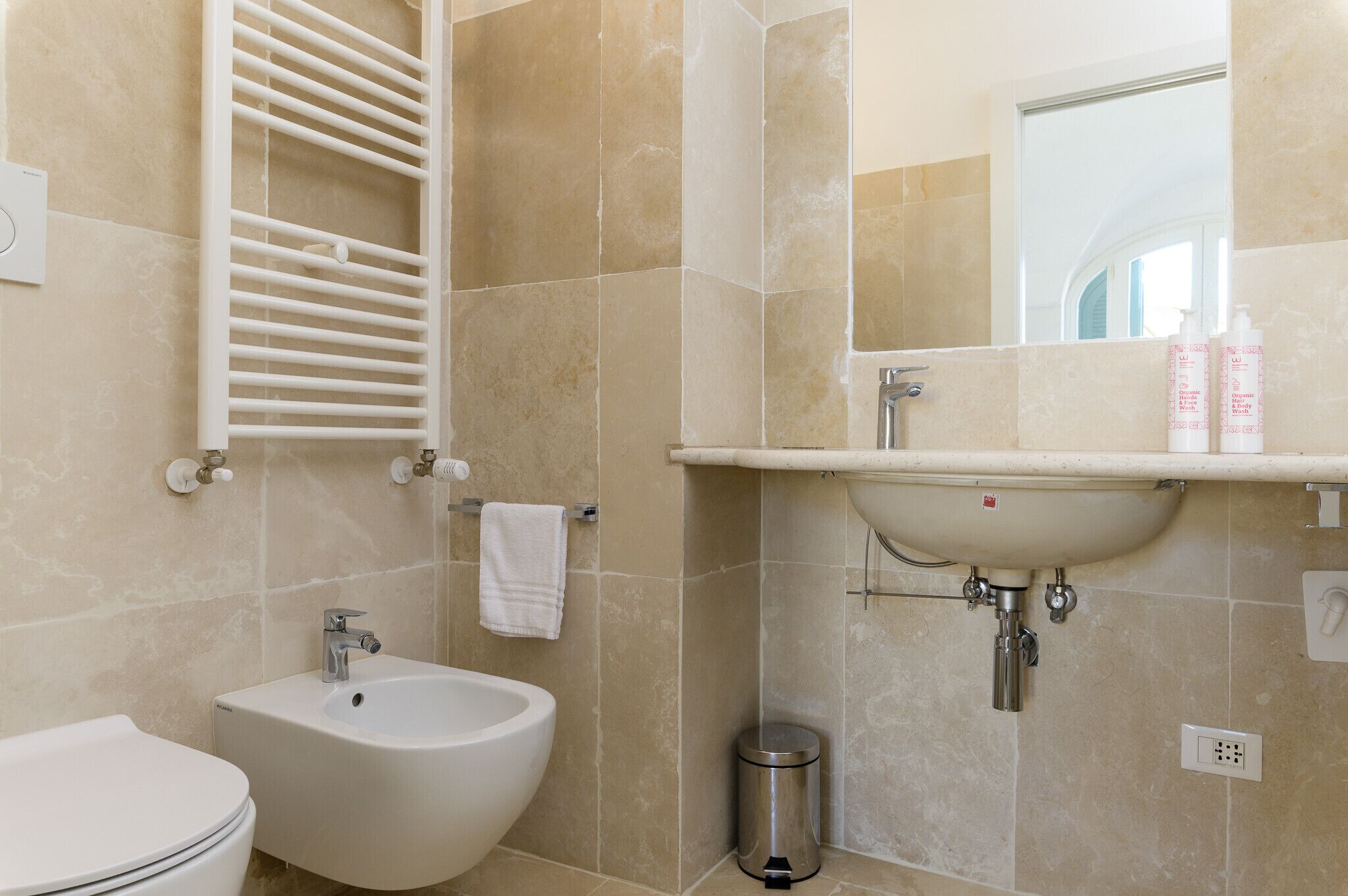 Ein Badezimmer mit Bidet, Waschbecken, Spiegel und Handtuchhalter.