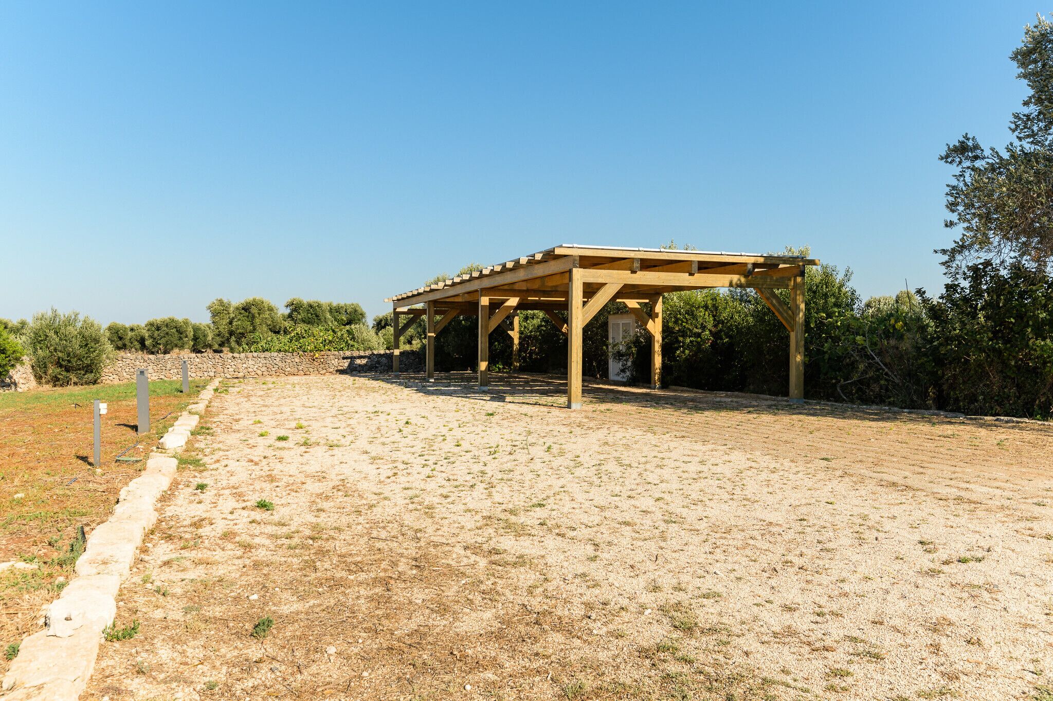 Una estructura de pérgola de madera en un campo abierto con cielo despejado.