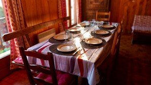Une table à manger dressée pour quatre personnes, avec une nappe à rayures, des chaises en bois et un chandelier en guise de centre de table.