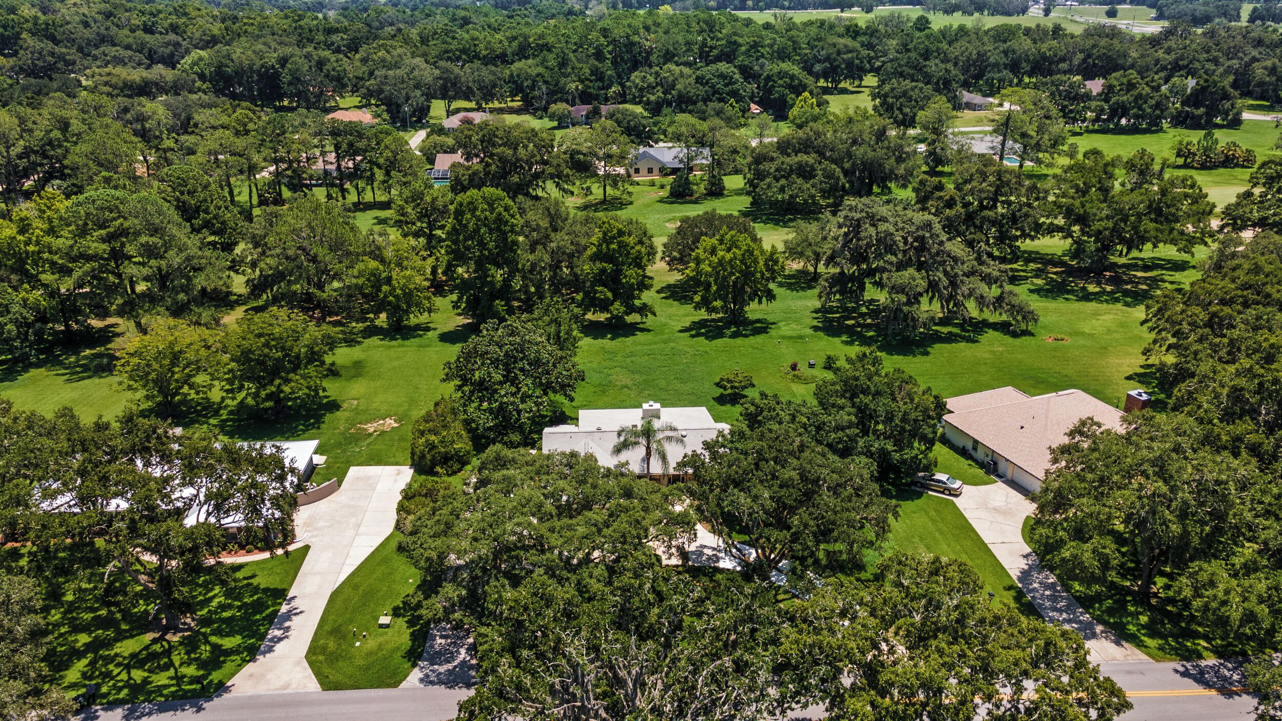 An aerial view of a residential area with houses, green lawns, and trees.