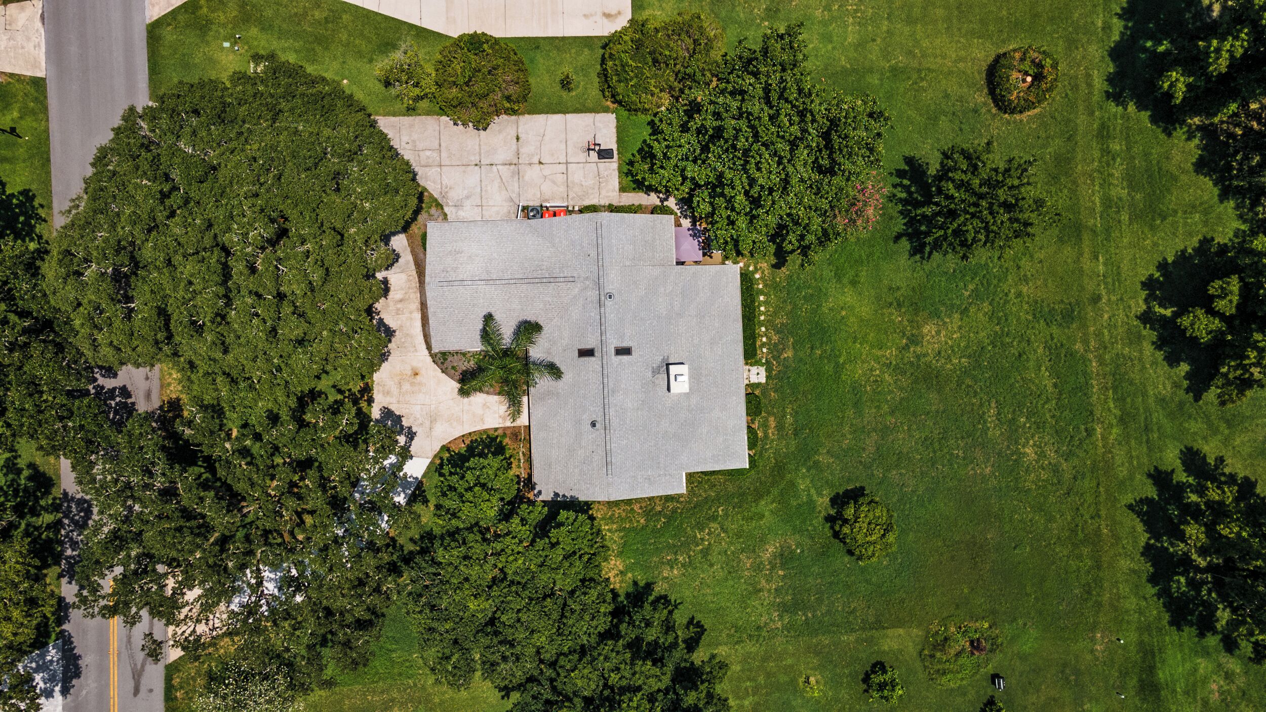 An aerial view of a building with a flat roof, surrounded by green lawns and trees.