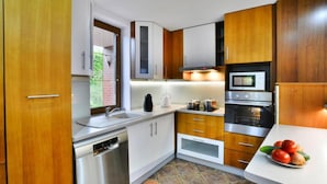 Una cocina compacta con armarios de madera, electrodomésticos de acero inoxidable y un salpicadero de azulejos.