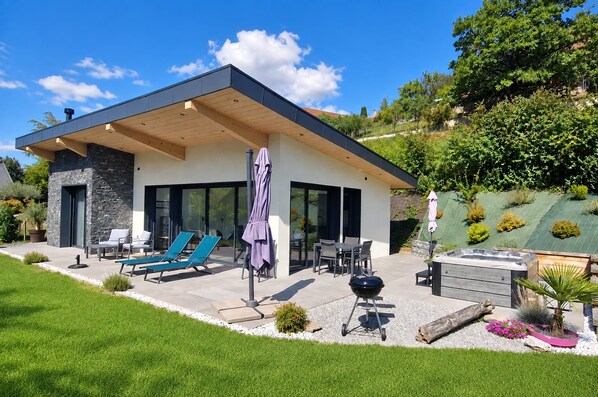 A modern house with a patio, outdoor seating, and a barbecue area.