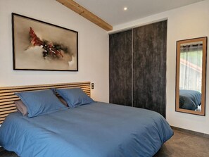 Un dormitorio con cama, un cuadro abstracto grande, un armario y una ventana con vistas.