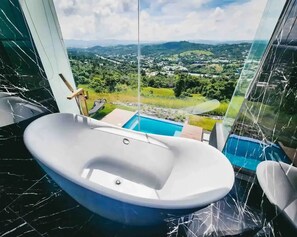 A modern bathroom with a freestanding bathtub, a small pool, and a view of a lush landscape. - 𝗟𝗮 𝗖𝗮𝘀𝗶𝘁𝗮 𝗡𝗲𝗴𝗿𝗮 𝗲𝗻 𝗖𝗮𝘆𝗲𝘆 (Barrio Beatriz)