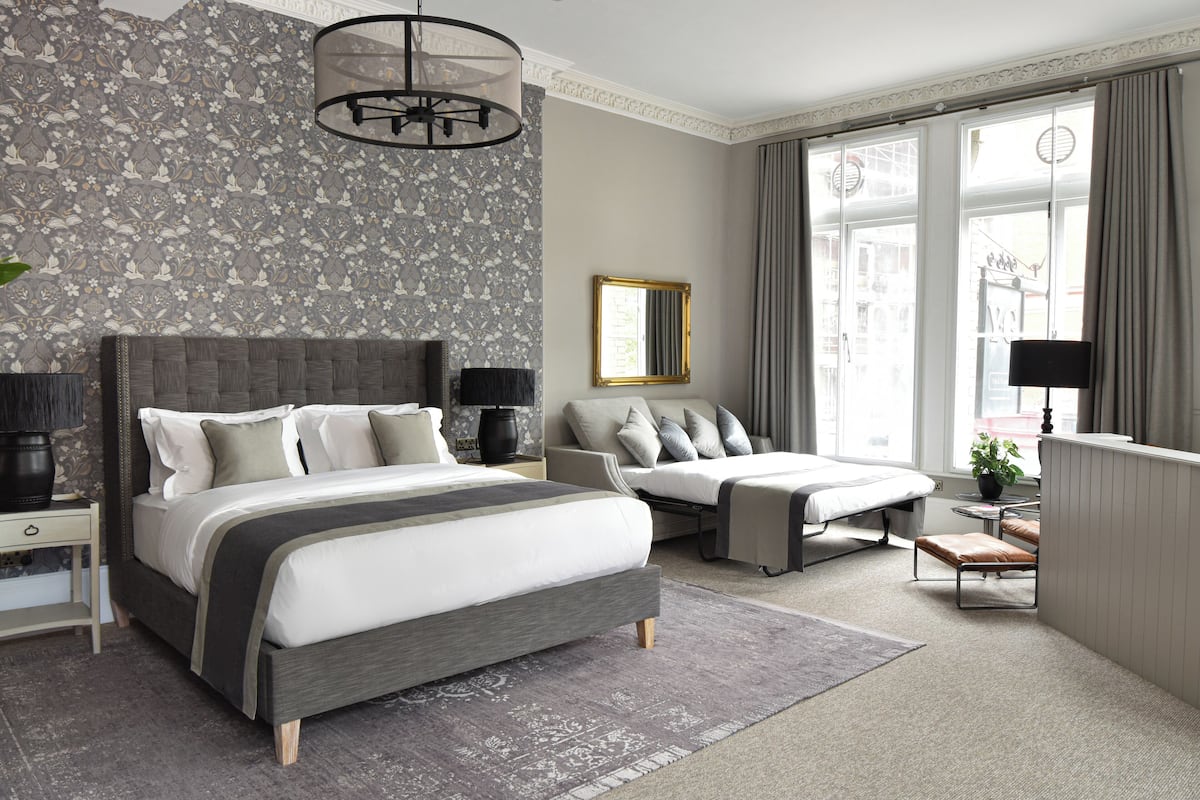 A modern bedroom with a large bed, a sofa, and a small table.