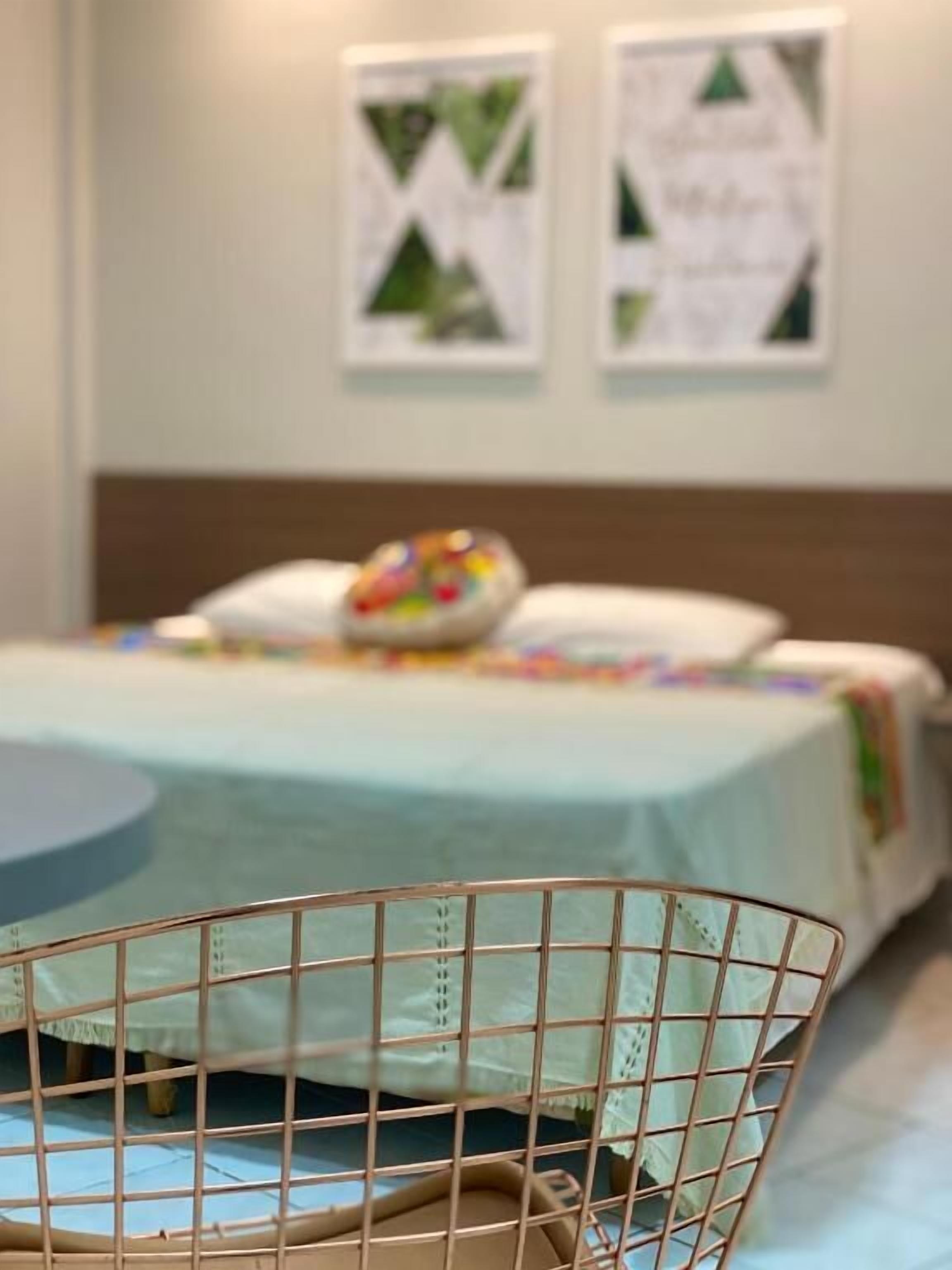 Una habitación de hotel con una cama, una mesita redonda y una silla metálica.