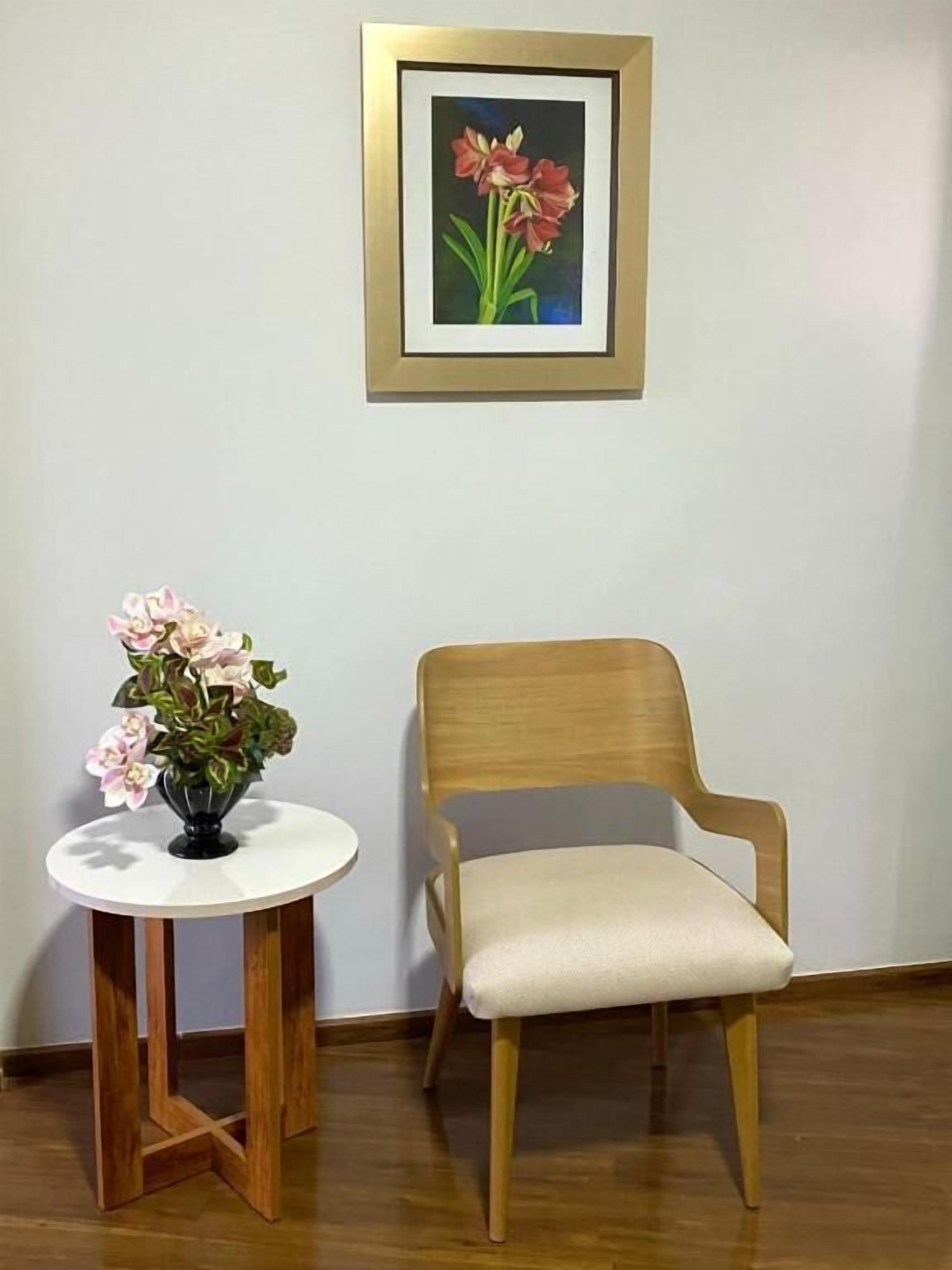 A room with a wooden chair and a small table with a vase of flowers.
