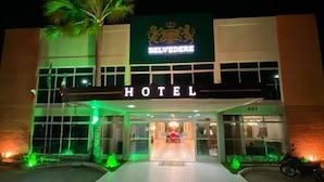 Un hôtel avec une enseigne bien visible indiquant « HÔTEL », un logo vert et blanc, et un palmier devant l’entrée.