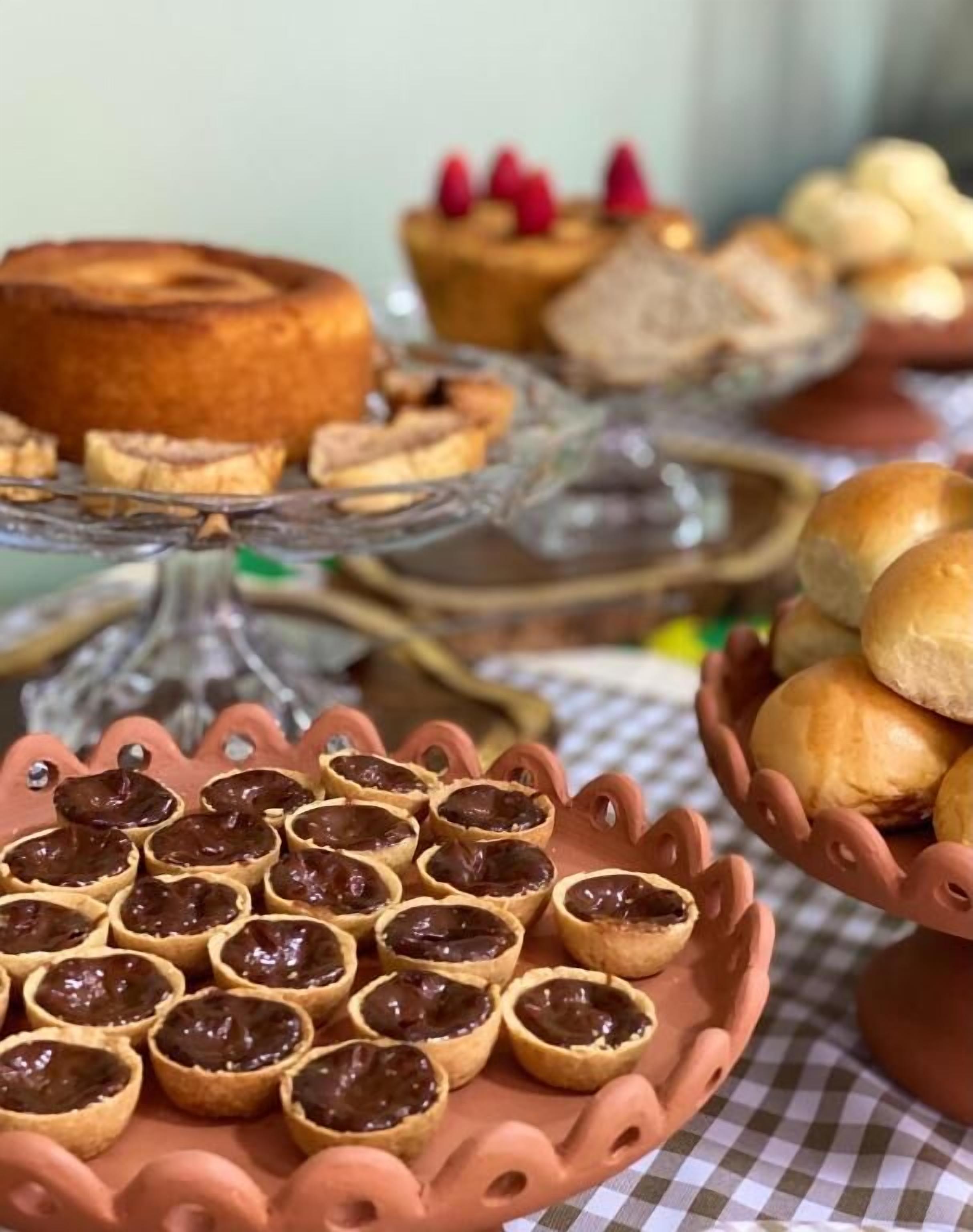 A variety of baked goods including tarts, a cake, and bread rolls on a table.