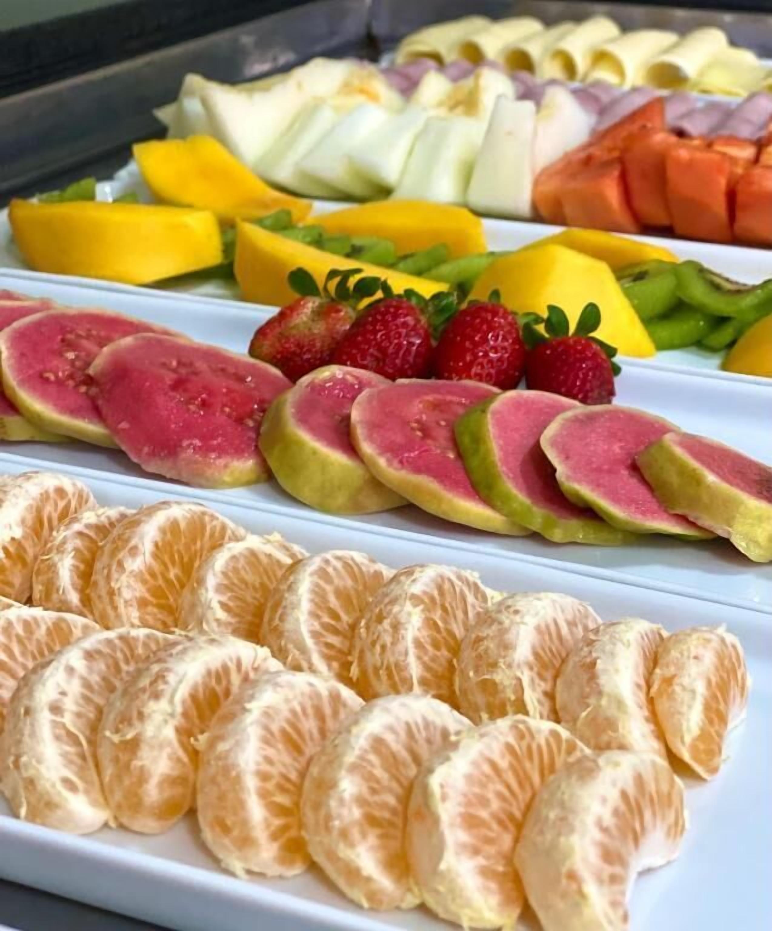 Una variedad de frutas cortadas, incluyendo mango, kiwi, fresas y cítricos, dispuestas en un plato.