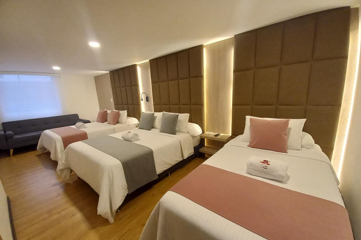 Une chambre d’hôtel avec deux lits, un canapé et une grande fenêtre.
