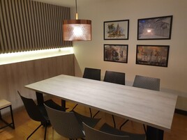 Un comedor moderno con una mesa de madera y sillas negras, una lámpara colgante y tres obras de arte enmarcadas en la pared.