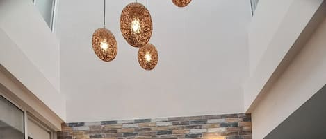 Un interior moderno con dos sillones de cuero alrededor de una mesa redonda, un centro de mesa decorativo con un cactus y una pared de ladrillo con dos luces fijadas a la pared.