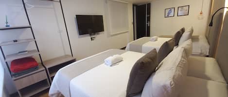 A hotel room with two beds, a TV, a shelf with towels, and a door marked '201'.